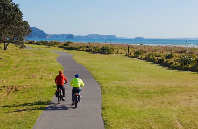 Two people riding their bikes in the Whangaparaoa Coastal Trail